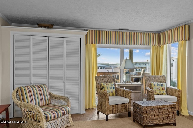 sitting room with a textured ceiling, light hardwood / wood-style floors, a wealth of natural light, and crown molding