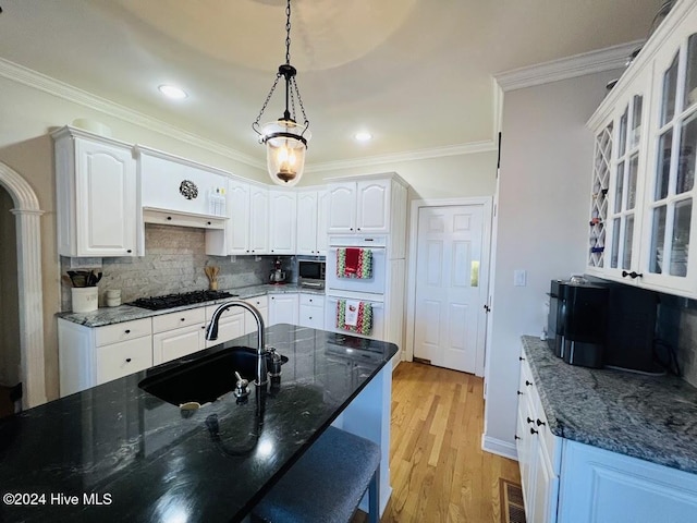 kitchen with pendant lighting, light wood-type flooring, white cabinetry, and sink