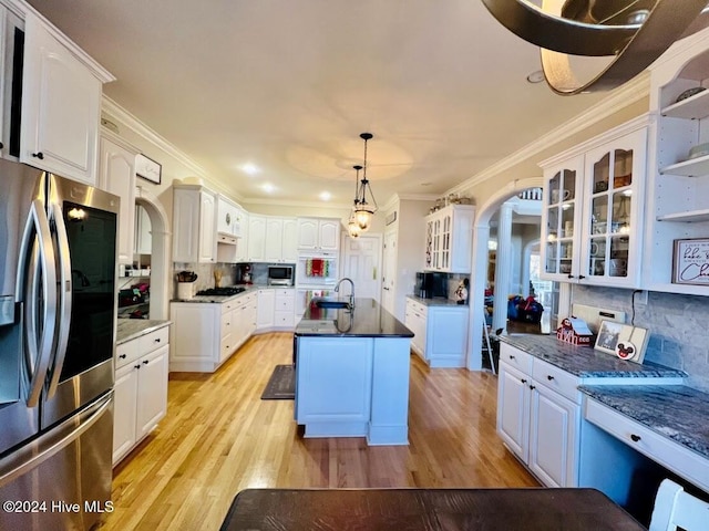 kitchen featuring white cabinets, decorative light fixtures, stainless steel appliances, and an island with sink