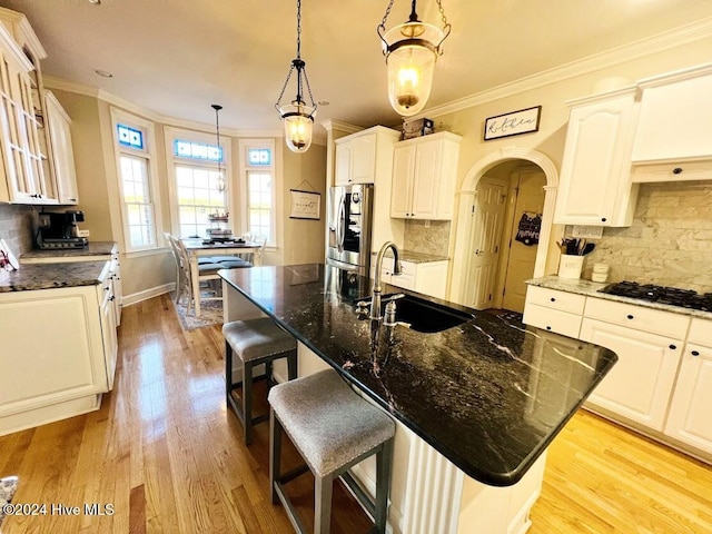 kitchen with black gas cooktop, sink, light hardwood / wood-style flooring, an island with sink, and tasteful backsplash