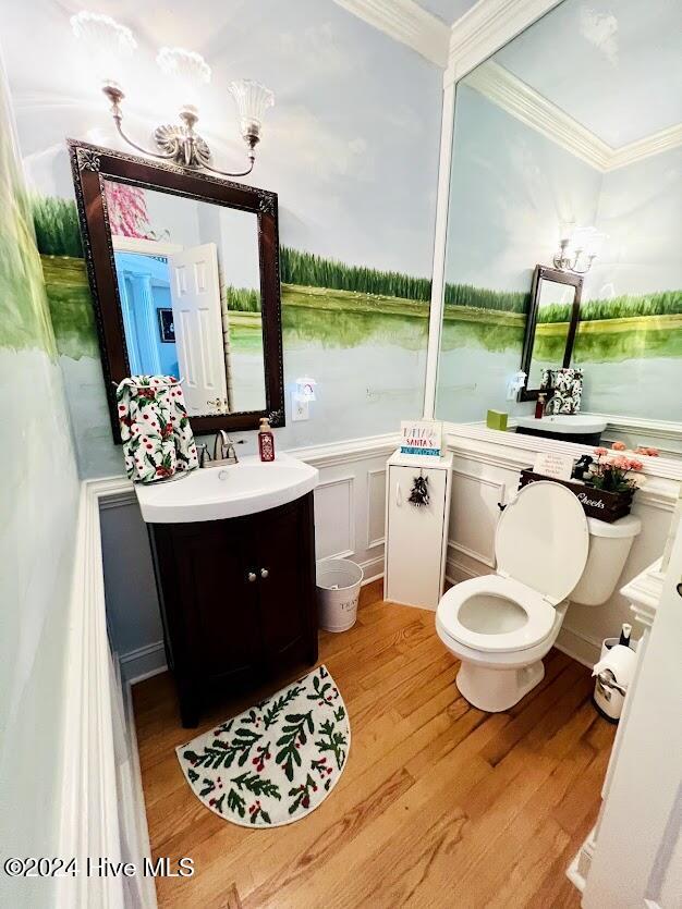 bathroom with crown molding, toilet, a water view, vanity, and hardwood / wood-style flooring