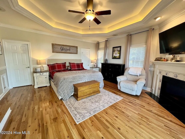 bedroom featuring a tray ceiling, ceiling fan, hardwood / wood-style floors, and ornamental molding