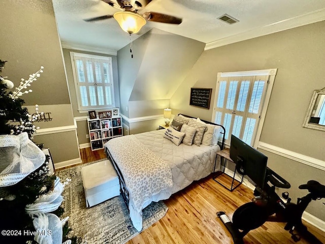 bedroom featuring ceiling fan, hardwood / wood-style floors, crown molding, and vaulted ceiling