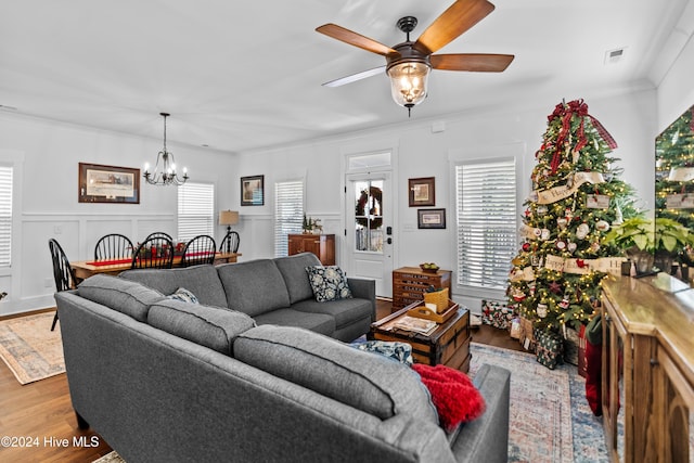 living room with plenty of natural light, light wood-type flooring, ceiling fan with notable chandelier, and ornamental molding