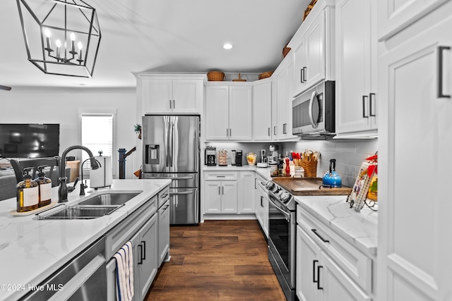 kitchen featuring white cabinetry, sink, dark hardwood / wood-style floors, decorative light fixtures, and appliances with stainless steel finishes