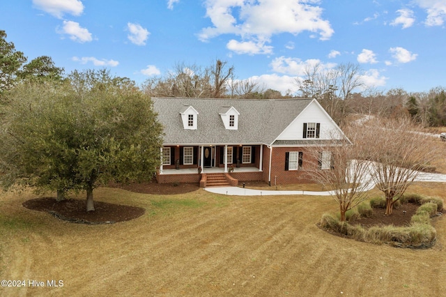 new england style home featuring a porch and a front lawn