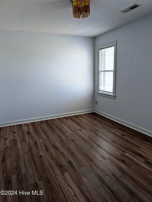 empty room featuring a textured ceiling and dark hardwood / wood-style floors