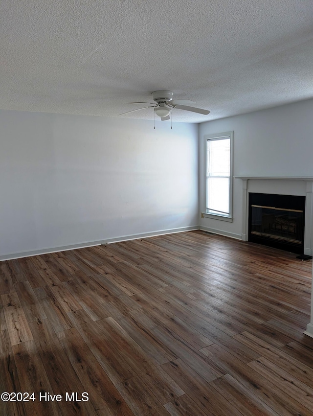 unfurnished living room featuring ceiling fan, dark wood-type flooring, and a textured ceiling