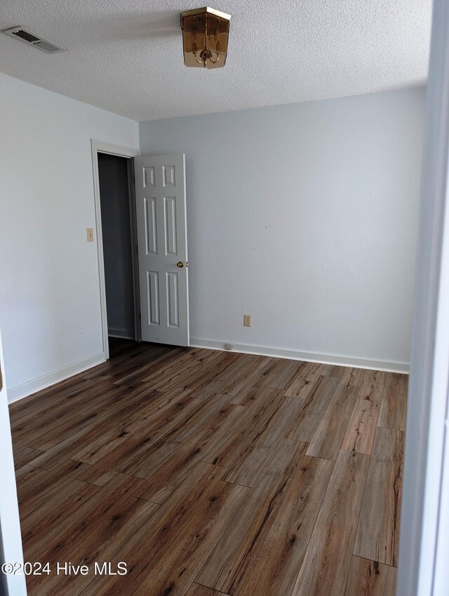 empty room featuring a textured ceiling and dark hardwood / wood-style floors