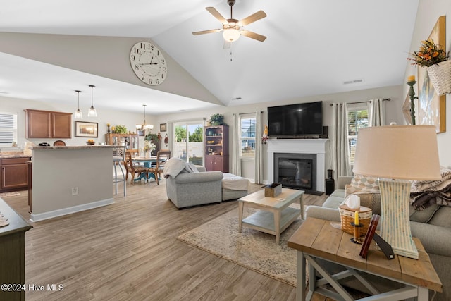 living room featuring plenty of natural light, light wood-type flooring, and ceiling fan with notable chandelier