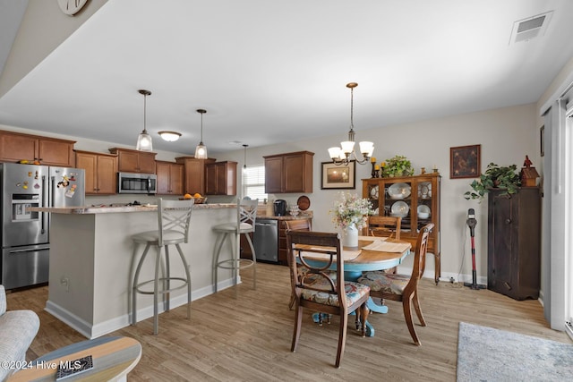 dining area featuring a notable chandelier and light wood-type flooring