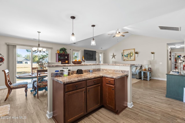 kitchen featuring light stone countertops, ceiling fan with notable chandelier, vaulted ceiling, pendant lighting, and light hardwood / wood-style floors