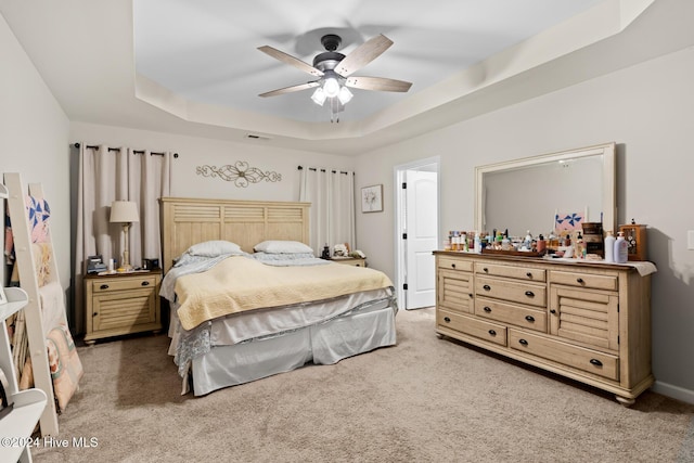 bedroom with carpet floors, a raised ceiling, and ceiling fan