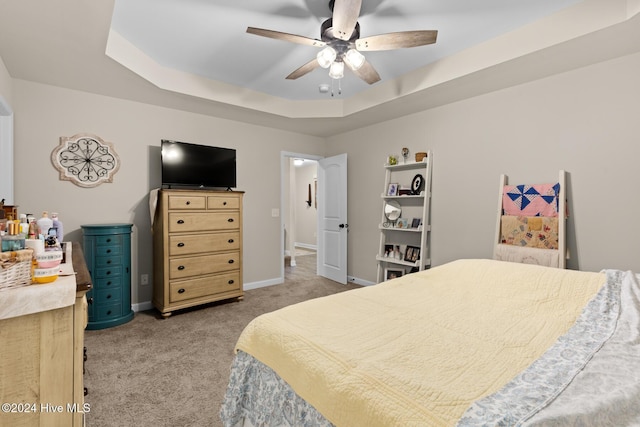 carpeted bedroom featuring ceiling fan and a tray ceiling