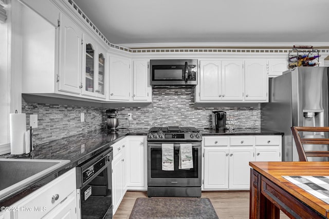 kitchen with white cabinets, light wood-type flooring, stainless steel appliances, and tasteful backsplash