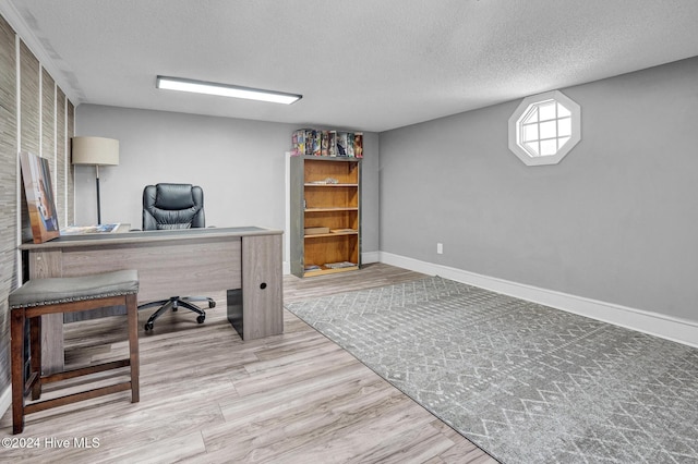 office with light wood-type flooring and a textured ceiling