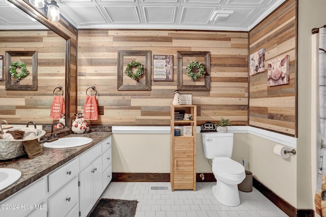 bathroom with tile patterned flooring, vanity, wood walls, and toilet