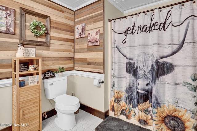 bathroom with tile patterned flooring, toilet, ornamental molding, and wood walls