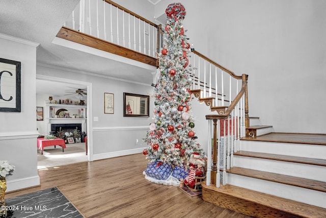 stairs featuring hardwood / wood-style floors, a textured ceiling, ceiling fan, and crown molding