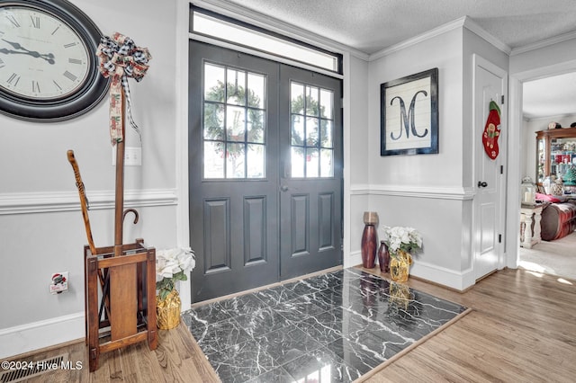 entryway with french doors, crown molding, hardwood / wood-style floors, and a textured ceiling