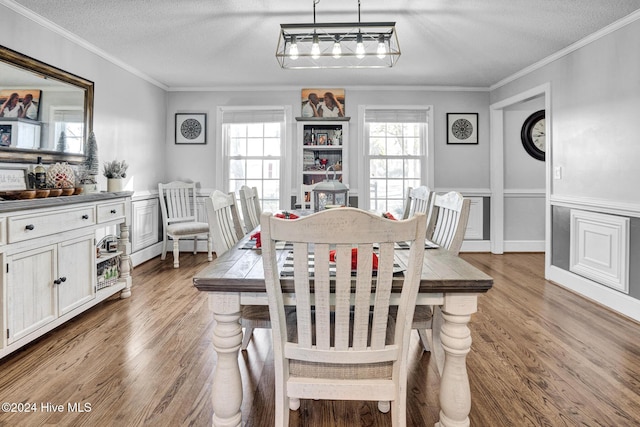 dining space with a textured ceiling, light wood-type flooring, and ornamental molding