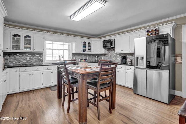 kitchen with white cabinets, crown molding, decorative backsplash, light wood-type flooring, and stainless steel appliances