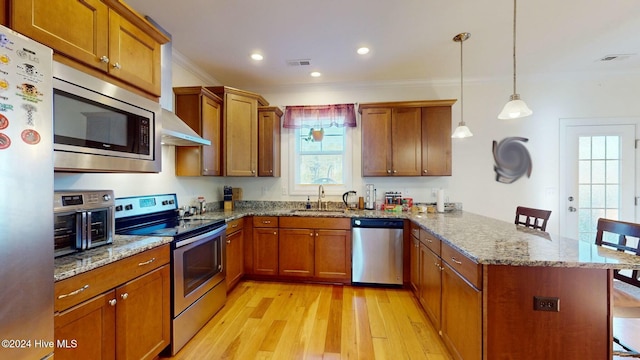 kitchen featuring crown molding, pendant lighting, light hardwood / wood-style floors, a breakfast bar area, and appliances with stainless steel finishes