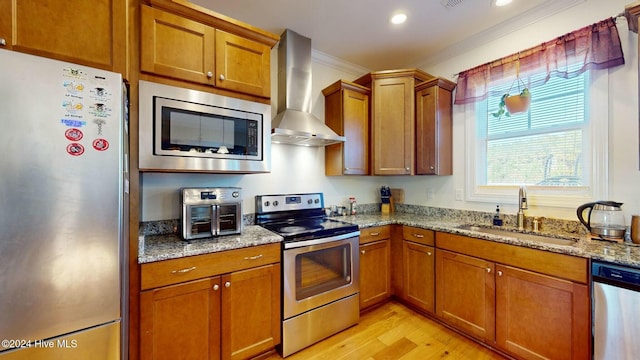 kitchen featuring sink, stainless steel appliances, wall chimney range hood, light hardwood / wood-style flooring, and ornamental molding