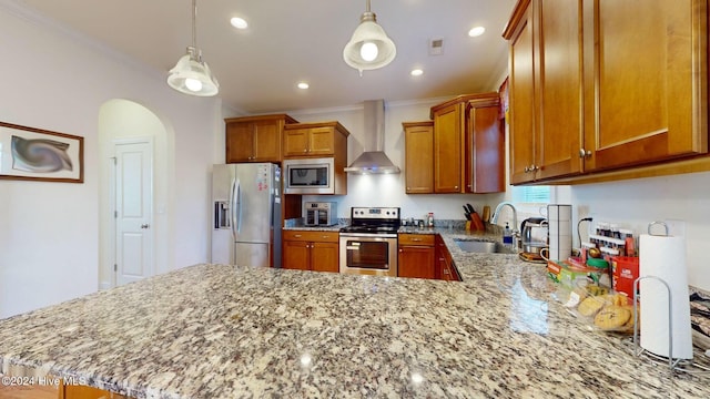 kitchen with stainless steel appliances, crown molding, sink, wall chimney range hood, and pendant lighting