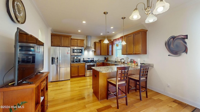 kitchen featuring kitchen peninsula, appliances with stainless steel finishes, hanging light fixtures, and wall chimney range hood