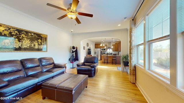 living room with ceiling fan, light wood-type flooring, and ornamental molding