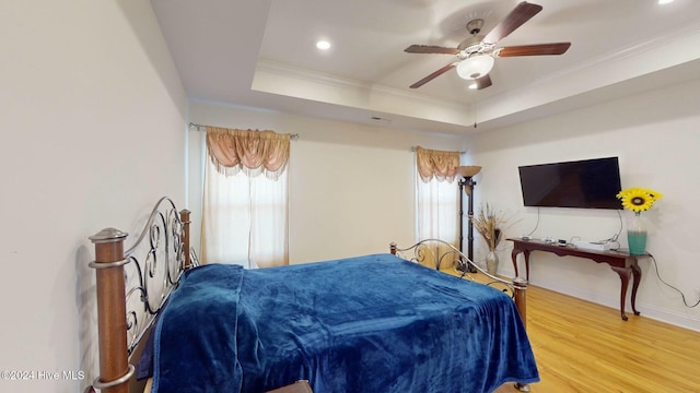 bedroom with a raised ceiling, ceiling fan, hardwood / wood-style floors, and ornamental molding