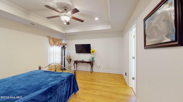 bedroom with a raised ceiling, ceiling fan, ornamental molding, and hardwood / wood-style flooring