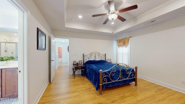 bedroom featuring ceiling fan, light hardwood / wood-style floors, ornamental molding, and a tray ceiling