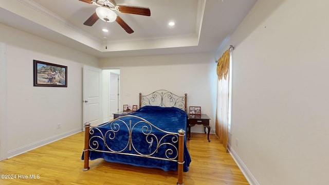 bedroom with ornamental molding, hardwood / wood-style flooring, ceiling fan, and a tray ceiling