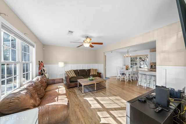 living room with light hardwood / wood-style floors and ceiling fan with notable chandelier