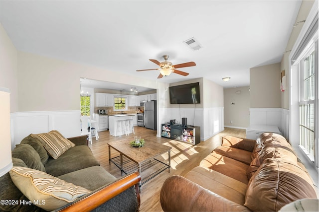 living room with a wealth of natural light, ceiling fan, and light hardwood / wood-style floors