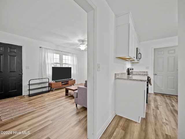 kitchen featuring white cabinetry, light hardwood / wood-style flooring, light stone countertops, and appliances with stainless steel finishes