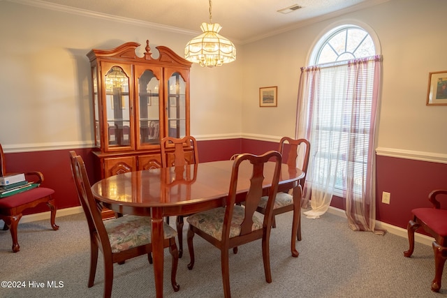 dining room featuring carpet, crown molding, and a chandelier