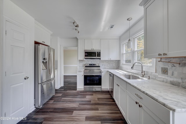 kitchen with backsplash, stainless steel appliances, sink, pendant lighting, and white cabinetry