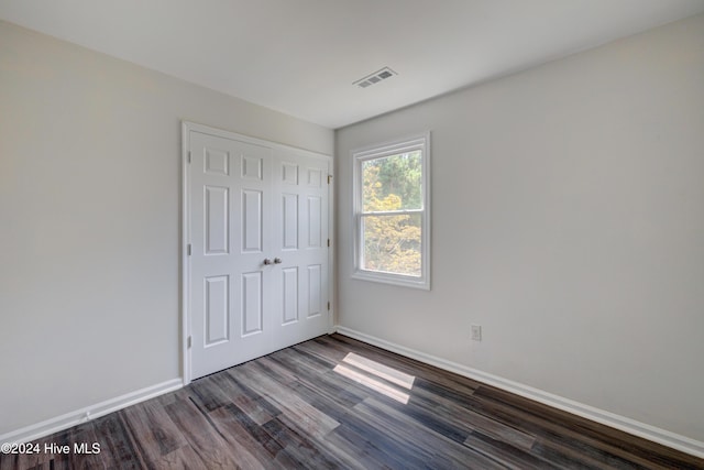 unfurnished bedroom with dark wood-type flooring and a closet