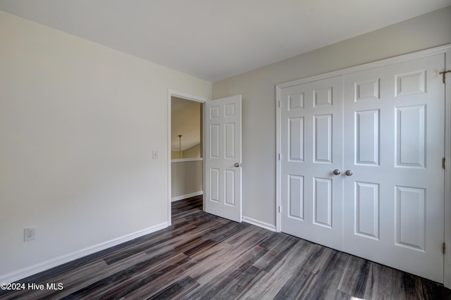 unfurnished bedroom with dark hardwood / wood-style flooring and a closet