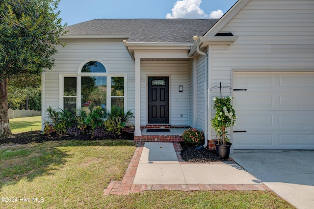 doorway to property with a yard and a garage