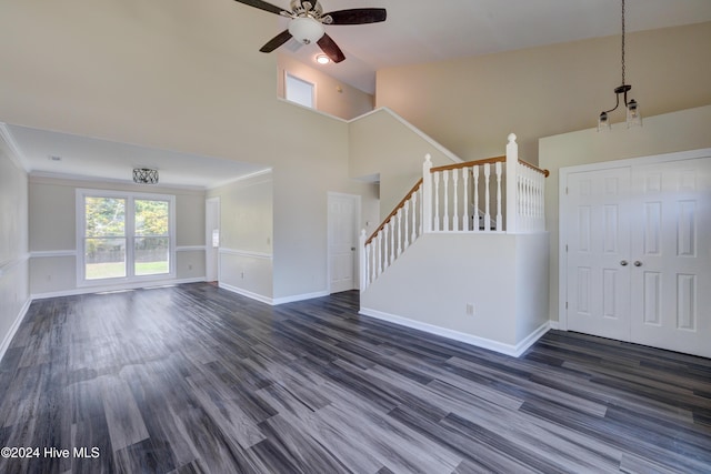 unfurnished living room with ceiling fan with notable chandelier, crown molding, and dark wood-type flooring