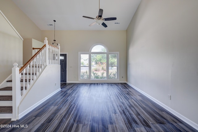 unfurnished living room with a high ceiling, ceiling fan, and dark wood-type flooring