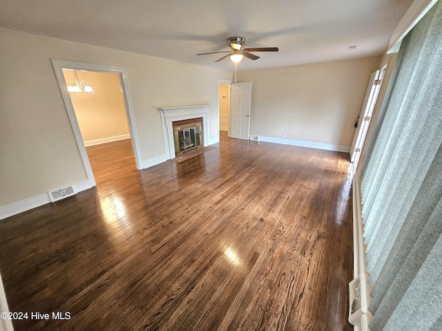 unfurnished living room with ceiling fan with notable chandelier and dark hardwood / wood-style floors