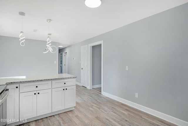 kitchen featuring light stone countertops, white cabinetry, light hardwood / wood-style flooring, and pendant lighting