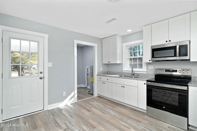 kitchen featuring sink, light hardwood / wood-style flooring, light stone countertops, appliances with stainless steel finishes, and white cabinetry