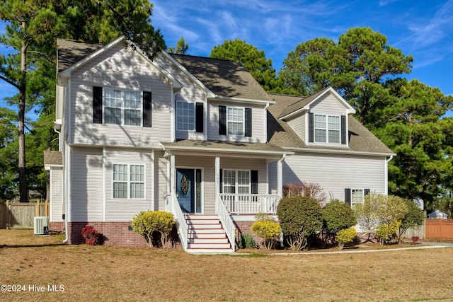 view of front of property featuring cooling unit, covered porch, and a front lawn