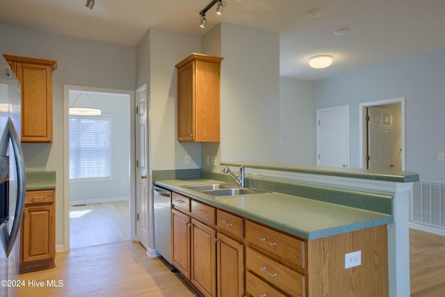 kitchen featuring kitchen peninsula, appliances with stainless steel finishes, light wood-type flooring, rail lighting, and sink